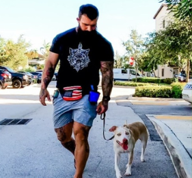 Dog trainer walking a tan and white dog on leash through a residential area, practicing calm heeling during a structured training walk.